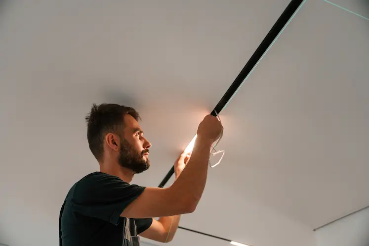 Local electrician installing a modern light fixture at a Yorkshire and the Humber property